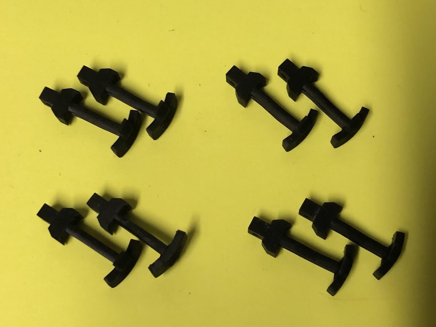 Set of four pairs of OO9 narrow gauge hook couplings for Kato 11-109 model railway chassis shown on a plain background