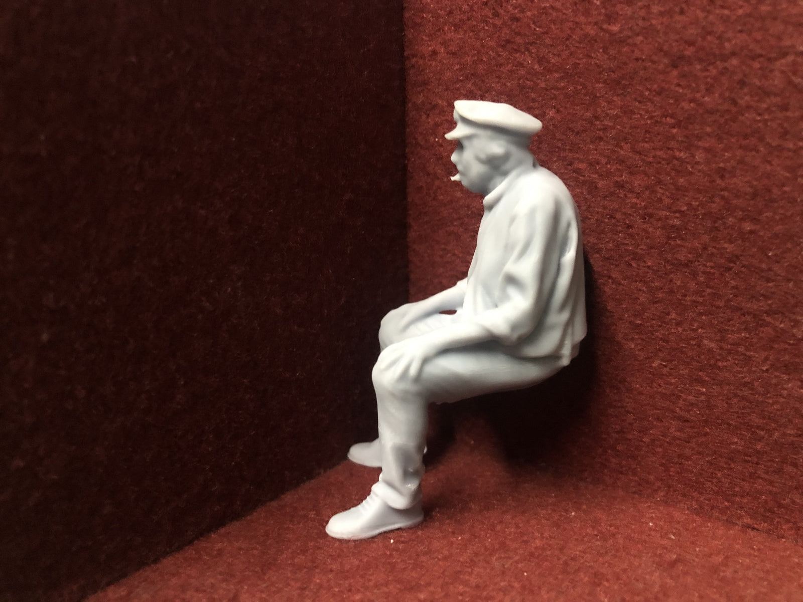 Unpainted 16mm 1:19 scale seated male figure in cap for SM32 garden railway layouts, suitable as a driver or resting passenger