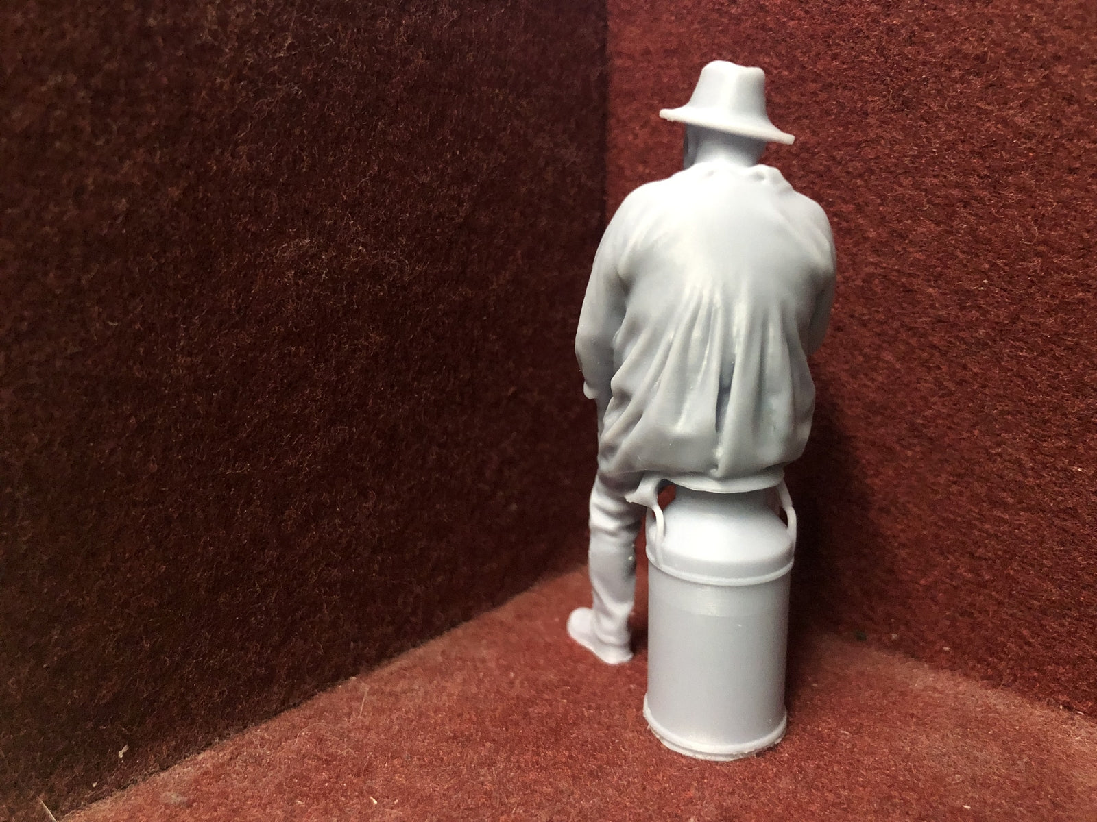 Unpainted G-scale 1:22.5 farmer figure sitting on a milk churn model railway accessory, 3D scanned from a real person