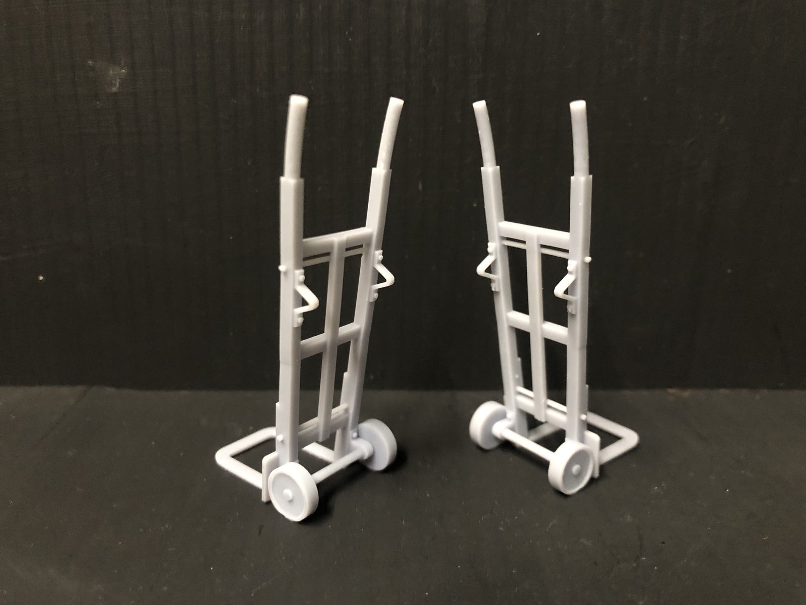 Unpainted GN15 G scale pair of resin sack trolleys for model railway platforms or workshops, shown next to a figure for size.