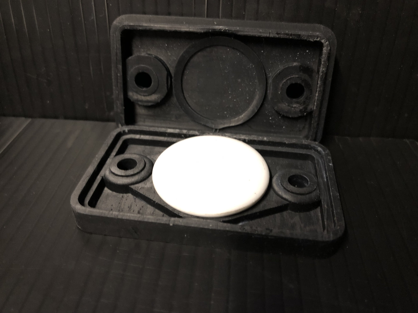 Black covert AirTag case styled as a small electronics box with heatsink fins for discreet tracking on vehicles or equipment