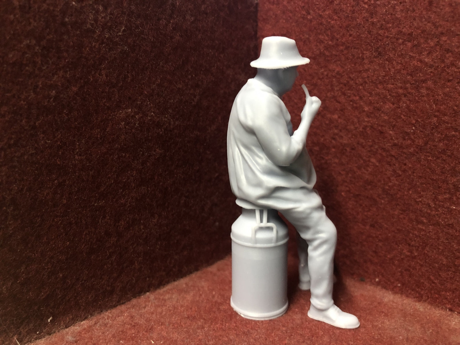 Unpainted G-scale 1:22.5 farmer figure sitting on a milk churn model railway accessory, suitable for GN15 layouts.