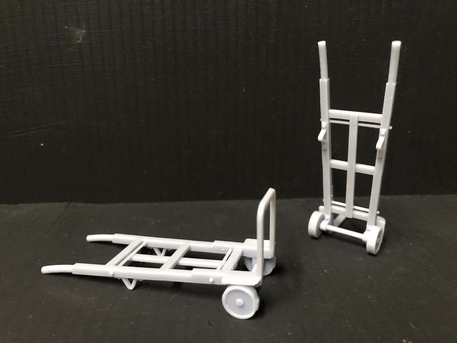 Unpainted GN15 G scale pair of resin sack trolleys for model railway platforms or workshops, shown next to a figure for size.