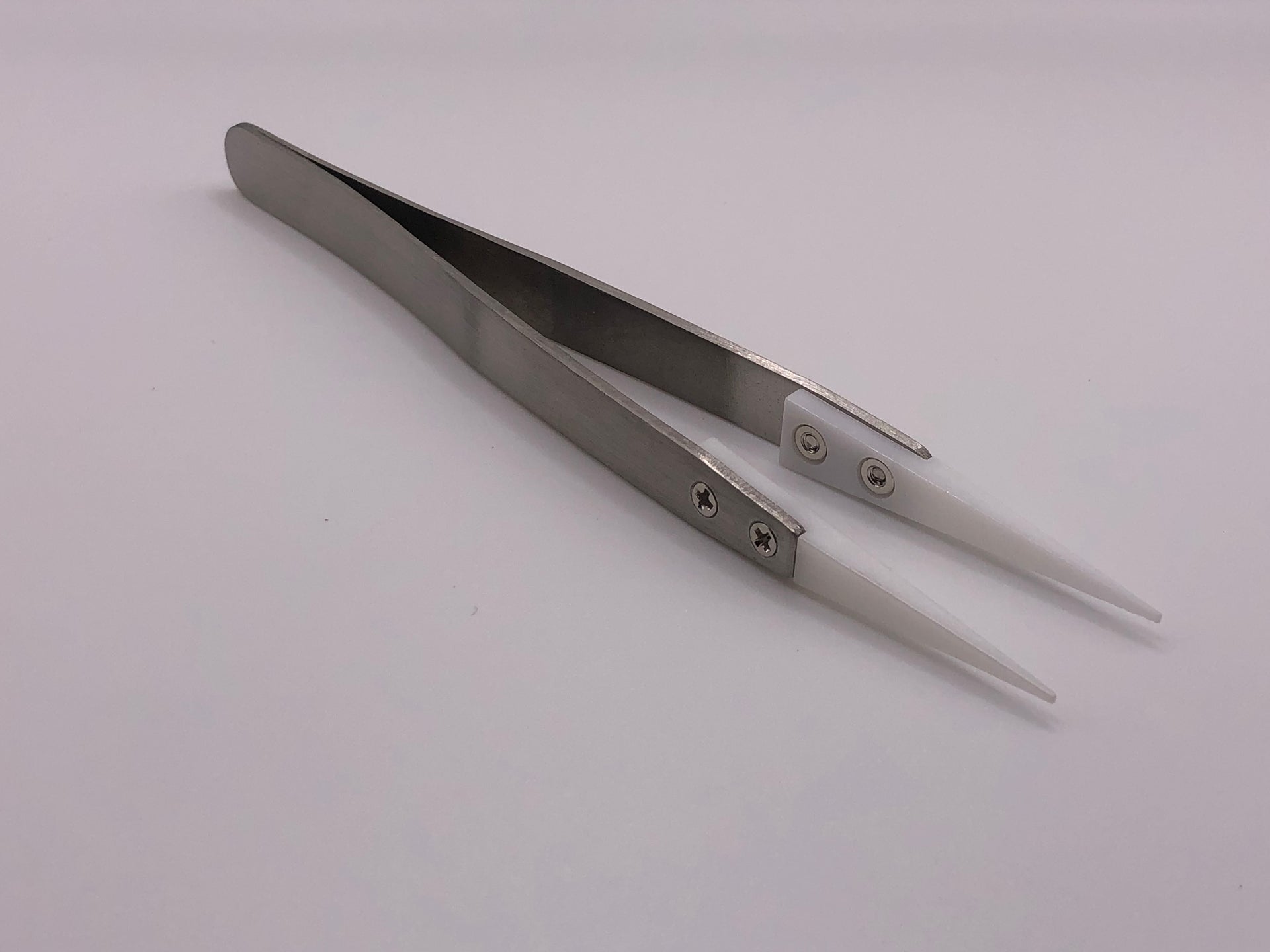 Fine-point stainless steel tweezers with white ceramic heat-resistant tips, ideal for precise model railway and electronics work