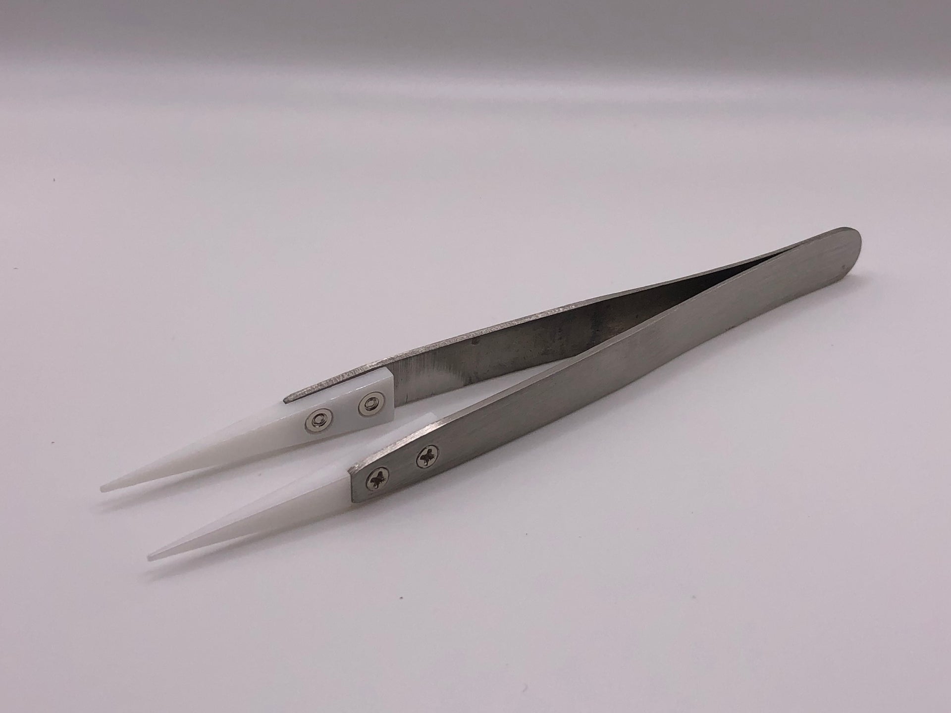 Fine-point stainless steel tweezers with white ceramic heat-resistant tips, ideal for precise model railway detailing work