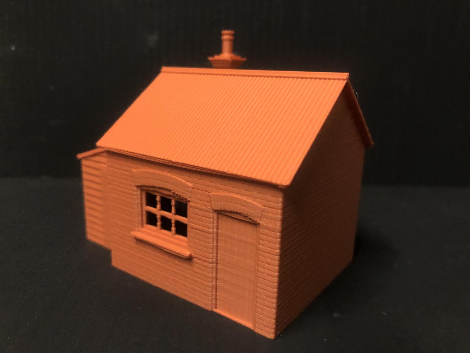 Unpainted OO9 scale brick workshop with lean-to model building, featuring corrugated walls and roof for narrow gauge railway layouts