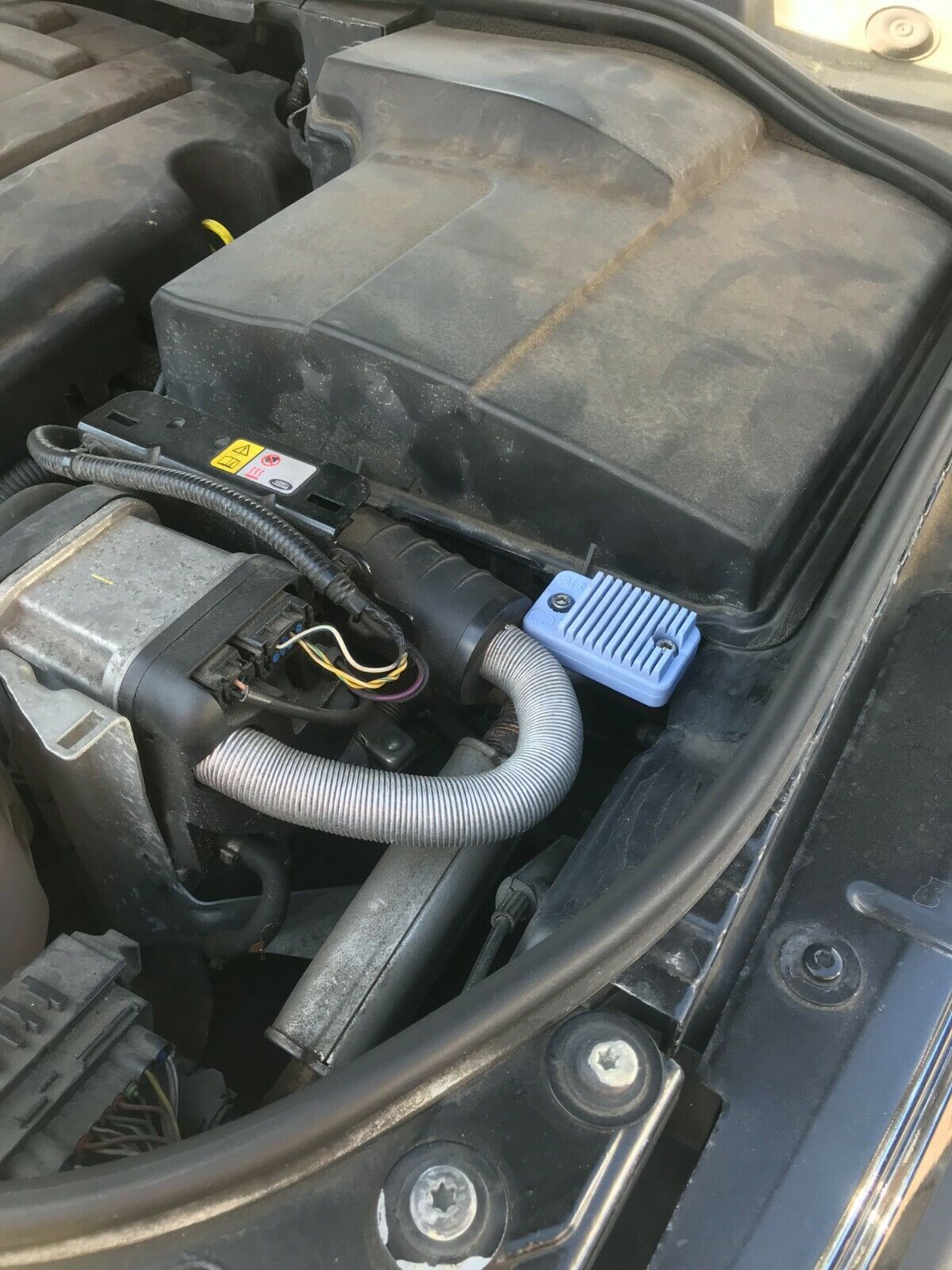 Black low-profile covert case for an Apple AirTag, shown mounted for discreet tracking on a car or motorbike