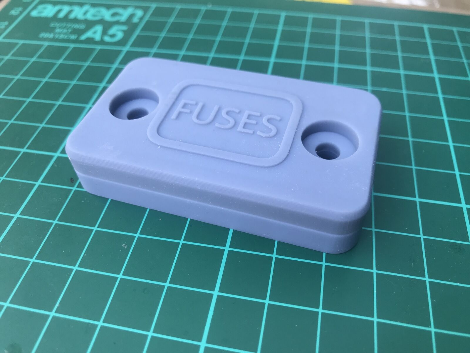 Covert Apple AirTag case disguised as a small black plastic block for discreet tracking on a car, motorbike or boat